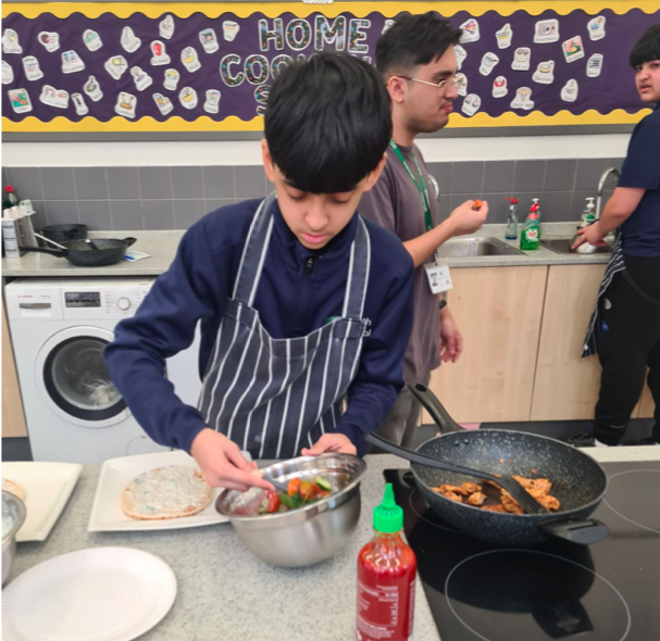 Heath School Home Cooking Skills student Yunus mixes up a salad to go with his chicken gyros recipe