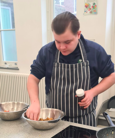 Heath School students adds seasoning to a chicken recipe